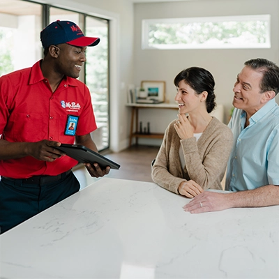 Mr. Rooter plumber sitting down with homeowners to discuss their plumbing