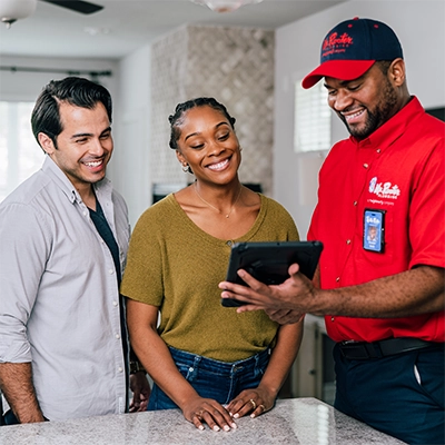 Mr. Rooter plumber reviewing completed plumbing work with a happy Connecticut couple