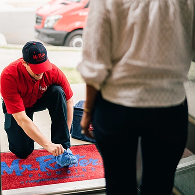 Mr. Rooter plumber putting on shoe covers at a homeowner’s door